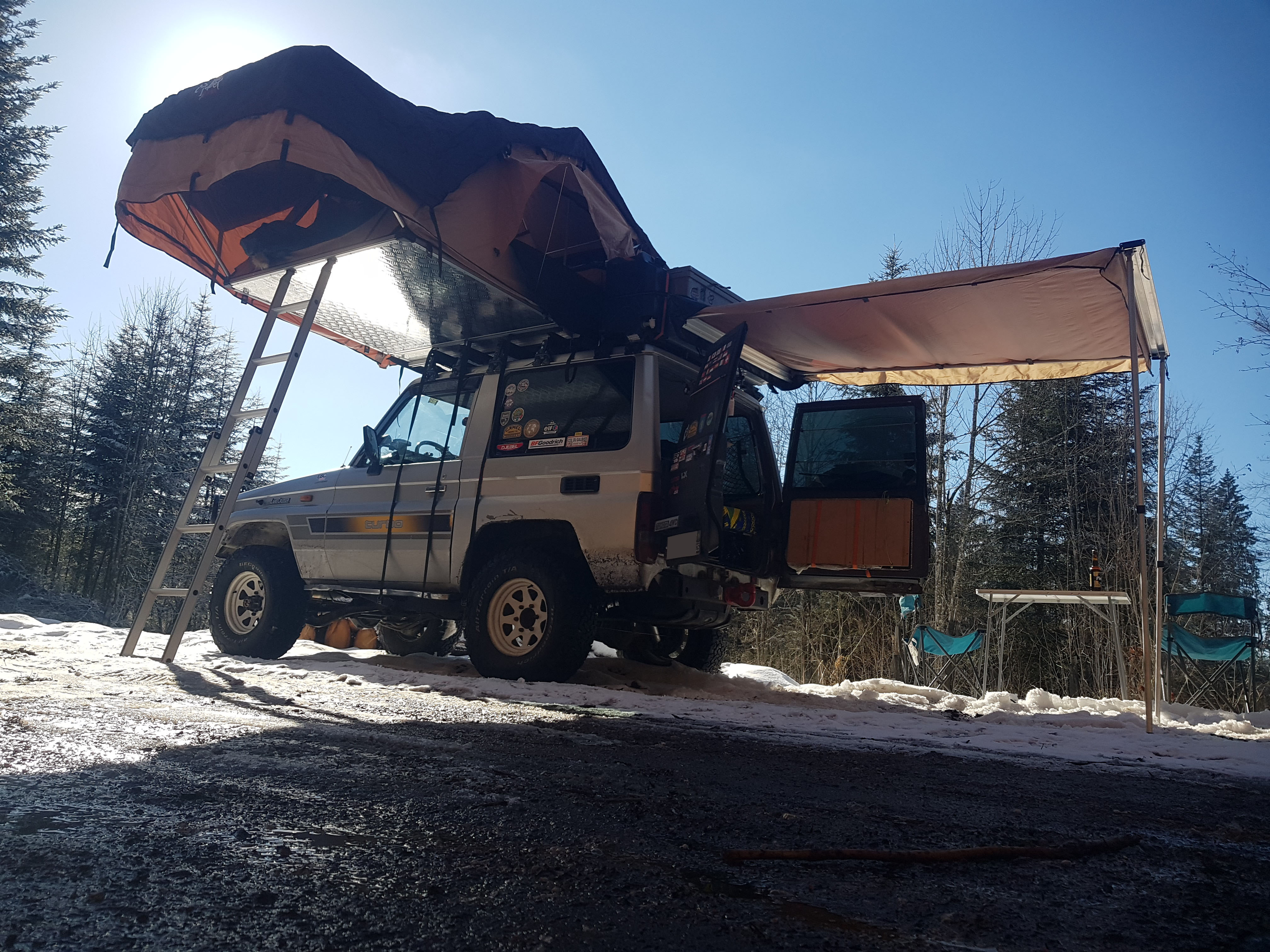 Photo arrière gauche du TOYOTA LAND CRUISER avec l'installation complète : tente de toît, annexe latérale et auvent arrière